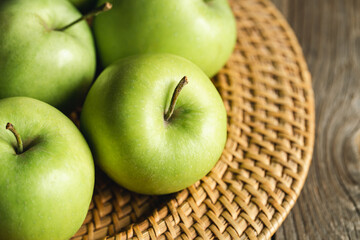 Wall Mural - Close-up, green apples in a straw plate close-up.