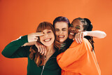 Fototapeta  - Multicultural female friends smiling and embracing each other in a studio