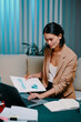 © DragonImages - Smiling businesswoman working on reports for presentation late at night