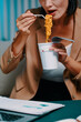 © DragonImages - Cropped image of businesswoman eating instant noodles when working on report late at night