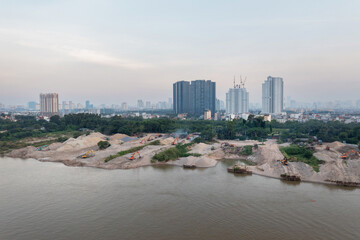 Red river with machines in construction site along river bank in Hanoi