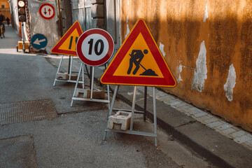 Road works sign on the road. Repair work of road signs and a bypass arrow on a background of blue sky.