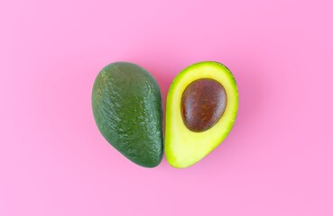 Half an avocado with a stone top view, isolated on a pink flat background. Ripe delicious avocado cut in the shape of a heart. The concept of love for healthy vegan food. 3d render illustration.