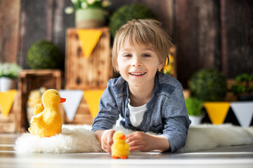 Poster - Cute young preschool child, boy, playing with ducks at home, beautiful spring decoration for birthday