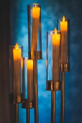 Wall Mural - Vertical shot of long candles lighted on blur background