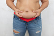 © Юля Бурмистрова - Unrecognizable overweight, fat woman holding sagging abdomen and try to put on small size jeans and hide fat on white background. Obesity problem, edema disease. Weight loss results. Need healthy diet