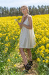 Beautiful woman with long blonde hair. He walks in the rapeseed field