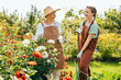© Iryna - Portrait of teenager granddaughter with senior grandmother laughing duringwork in garden, with flowers around.