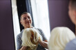 © Seventyfour - Portrait of mature bald woman trying on wigs looking in mirror and smiling