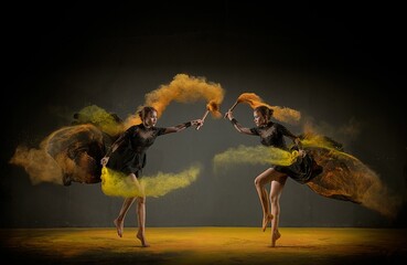 Models jumping with a drum filled with colorful powder on a yellow floor