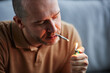 © Seventyfour - Adult man lighting up cigarette smoking at home for therapeutic purpose and medical treatment