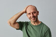© Seventyfour - Portrait of mature bald man smiling at camera and posing confidently with hand on head, copy space