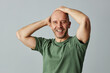 © Seventyfour - Waist up portrait of confident bald man smiling at camera and posing with hands on head