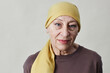 Front view portrait of smiling adult woman wearing headscarf and looking at camera against white