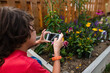 © Maria Manco/Stocksy - boy takes a photo of a butterfly in the flower garden