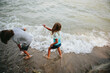 © Maria Manco/Stocksy - Kids throw rocks in water at beach
