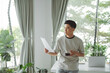 © Marc Tran/Stocksy - Young businessman drinking coffee and looking at statistical data