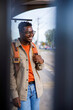 © Jovo Jovanovic/Stocksy - Smiling man with backpack waiting for transport at city tram station