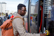 © Jovo Jovanovic/Stocksy - Man with backpack pressing button to open the tram door at station