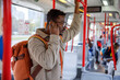 © Jovo Jovanovic/Stocksy - Man with backpack putting on wireless earphones in tram