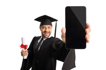 Canvas Print - Man in a graduation gown holding a diploma and showing a smartphone