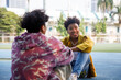 © Jovo Jovanovic/Stocksy - Two friends in casual outfit relaxing and talking outside at park