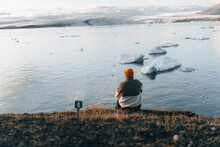 Alone Traveler Man Sitting At The Edge Of Rock Watching At Glacier