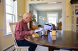 © Raymond Forbes LLC/Stocksy - Senior Man at Home Paying bills personal finance