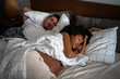 © Atolas/Stocksy - Pregnant couple sleeping in bed