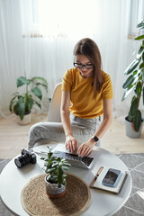 Wall Mural - Young woman photographer working at home using computer sitting at table at home