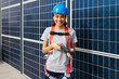 © BONNINSTUDIO/Stocksy - Smiling engineer female in front of solar power station