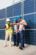 © BONNINSTUDIO/Stocksy - Workers discussing in front of solar power station