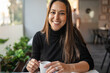 © Lupe Rodríguez/Stocksy - young woman sitting in a restaurant cafeteria