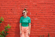 © Shava Cueva/Stocksy - woman with retro clothes smiling in front of a red brick wall