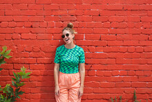 Woman With Retro Clothes Smiling In Front Of A Red Brick Wall