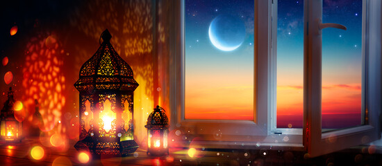 Wall Mural - ramadan kareem - arabic lanterns and window with moon at sunset - abstract defocused lights - eid ul
