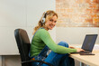 © BONNINSTUDIO/Stocksy - Smiling woman in headphones working on laptop