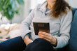 © Serena Burroughs/Stocksy - Middle aged woman relaxing on couch, reading e-book on a device
