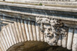 Stone faces on a historical bridge over the Seine River, in Paris, France.