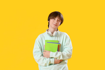 Canvas Print - Male student with copybooks on yellow background