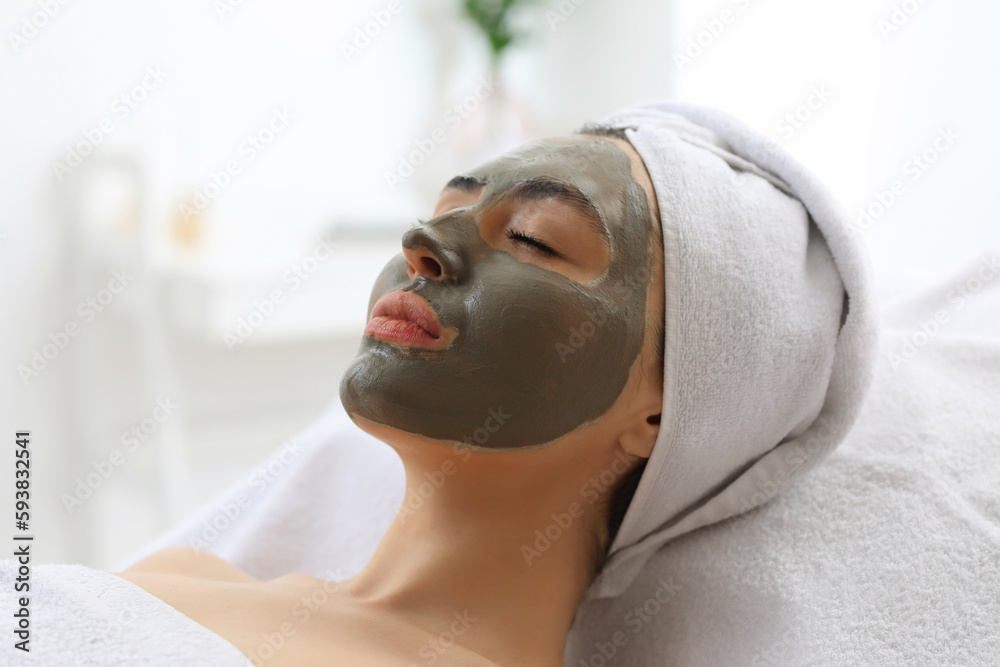 Young woman with applied clay mask in salon, closeup