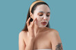 © Pixel-Shot - Young woman with sheet mask on blue background, closeup