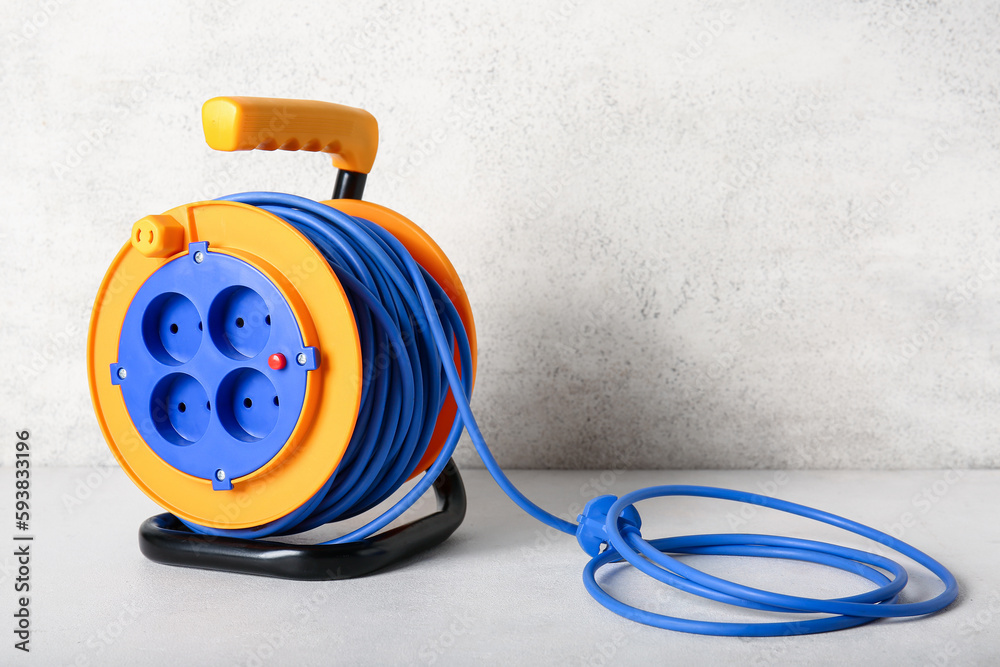 Extension electric cable reel on light background