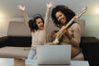 Mom with her daughter playing electric guitar together at home, happy family