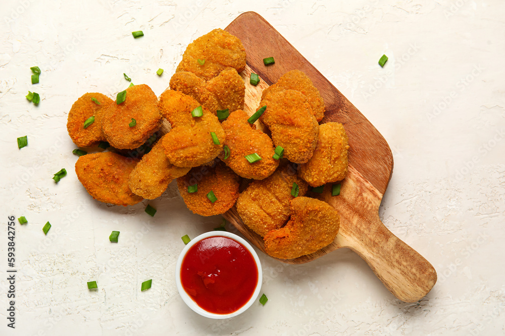 Wooden board with tasty nuggets and ketchup on light background