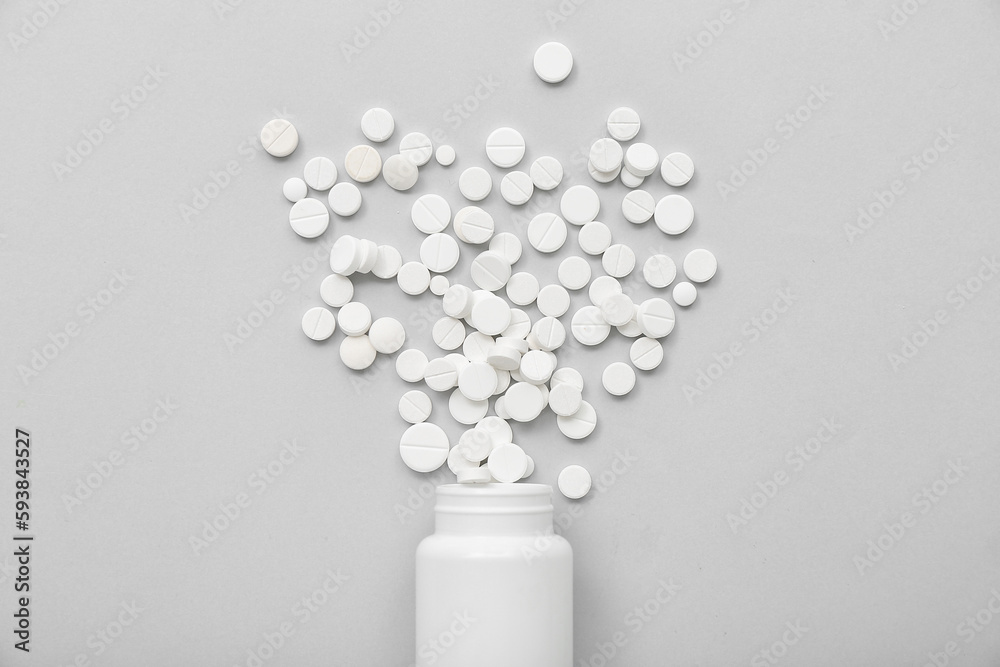 Bottle with white pills on grey background