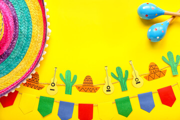 Wall Mural - Frame made of Mexican maracas, paper garland, flags and sombrero hat on yellow background