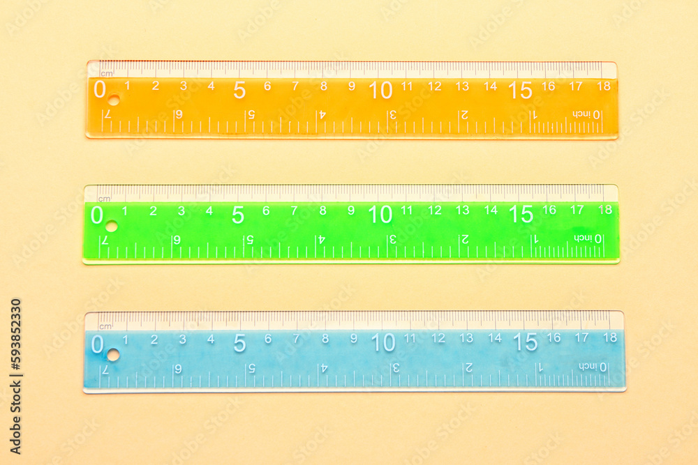 Colorful plastic rulers on beige background