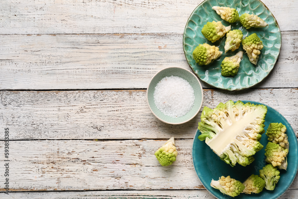Plates with romanesco cabbage on light wooden background