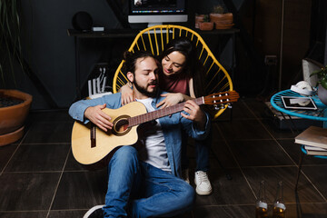 Wall Mural - young latin couple playing guitar in a romantic date, Girlfriend and boyfriend having fun at home at night in Mexico Latin America, hispanic people